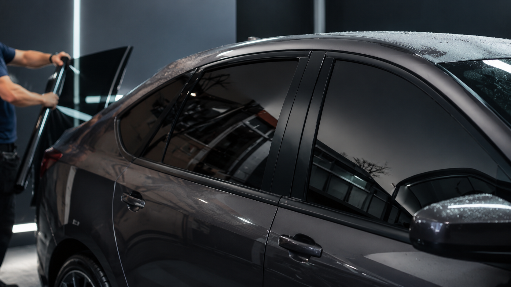 Technician applying tint film to a sedan
